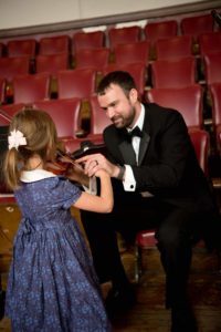 Melrose Schools Orchestra Director Luke Miller, seen here assisting a young student with the violin, has been named the state's Orchestra Director of the Year. (Courtesy Photo/Melrose Symphony Orchestra)