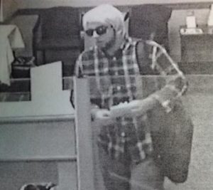 The Bedford Police Department is looking for a man who allegedly robbed Brookline Bank this morning. He is described as a white male with a brown beard, plaid long-sleeved shirt, dark sneakers, black backpack, sunglasses and possibly wearing a blonde wig. (Courtesy Photo).