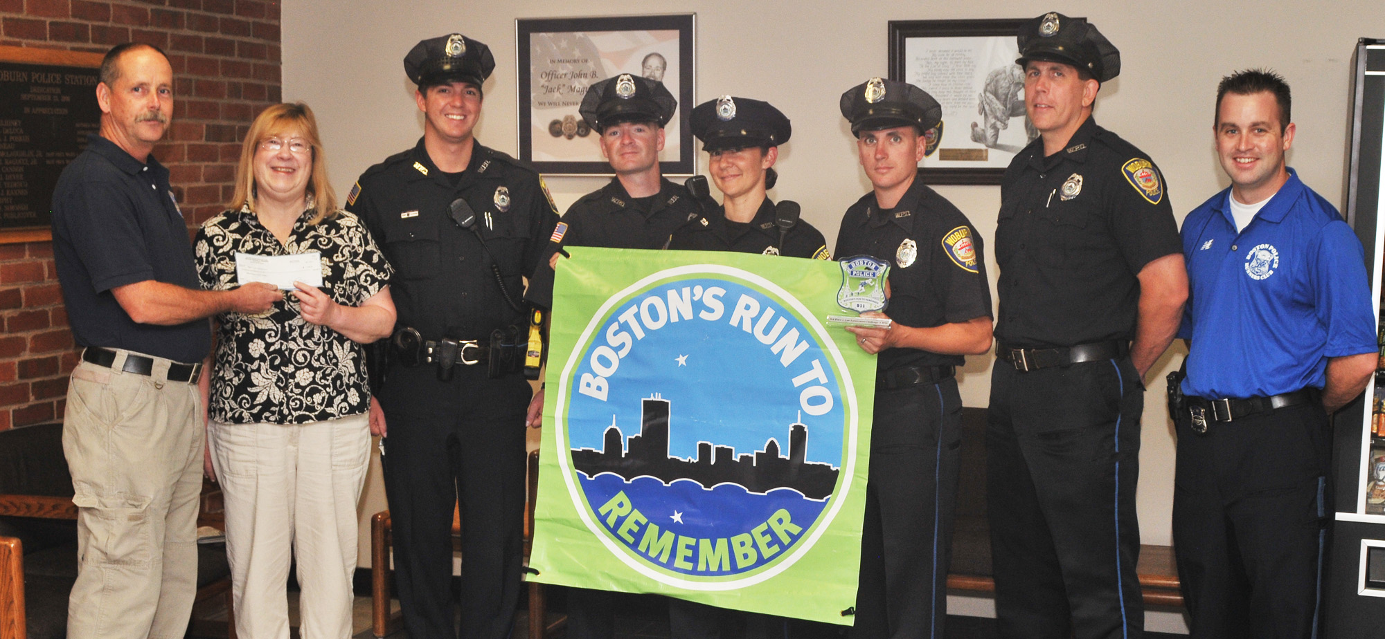Woburn Police Officer John Lally (l) presents a $2000 check to Woburn Council of Social Concern Food Pantry director Karen Colantrella. The money came from entry fees and 2nd place winnings from the Boston's Run to Remember - a half marathon - held recently. Woburn Police had 6 entrants in the race, and the top 5 times were calculated for a team score. WPD finished in 2nd place overall. Officers running the race (l-r) Erik Hill, Ed Chisholm, Cristina Bartolomeu, Ian Hunt, and Paul Doherty. Represnting Boston Police is Officer Jeffrey Cahill. Woburn Police Orricer Ian Hunt also was recognized for his winning the police officer division of the race. (Photo by JoeBrownPhotos.com for the Woburn Police Dpeartment)